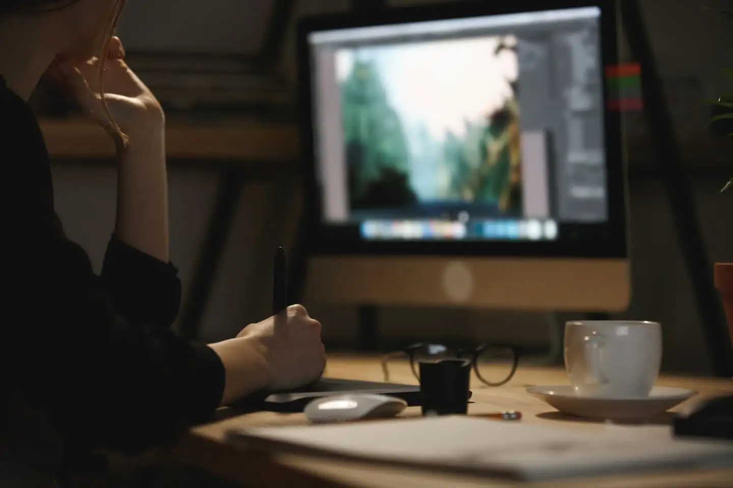 A designer working on brand artwork with a stylus at a desktop monitor